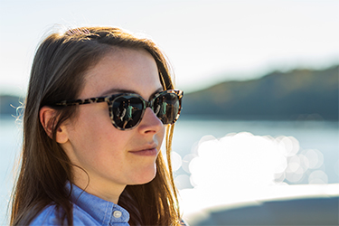 A woman wears tortoiseshell glasses outside.