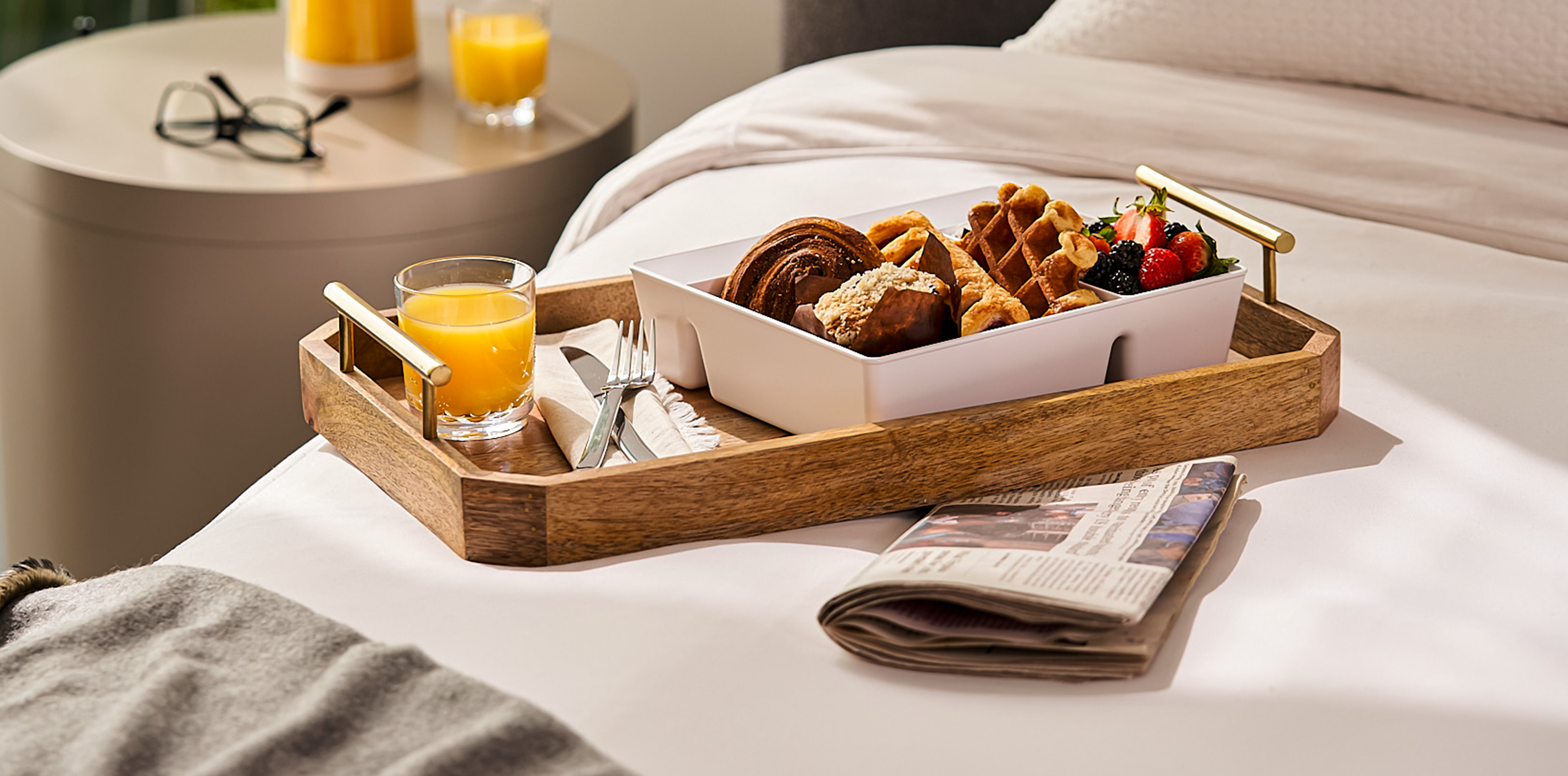 A tray with orange juice and a bento box of baked goods, waffles and fruit.  A tray with orange juice and a bento box of baked goods, waffles and fruit.