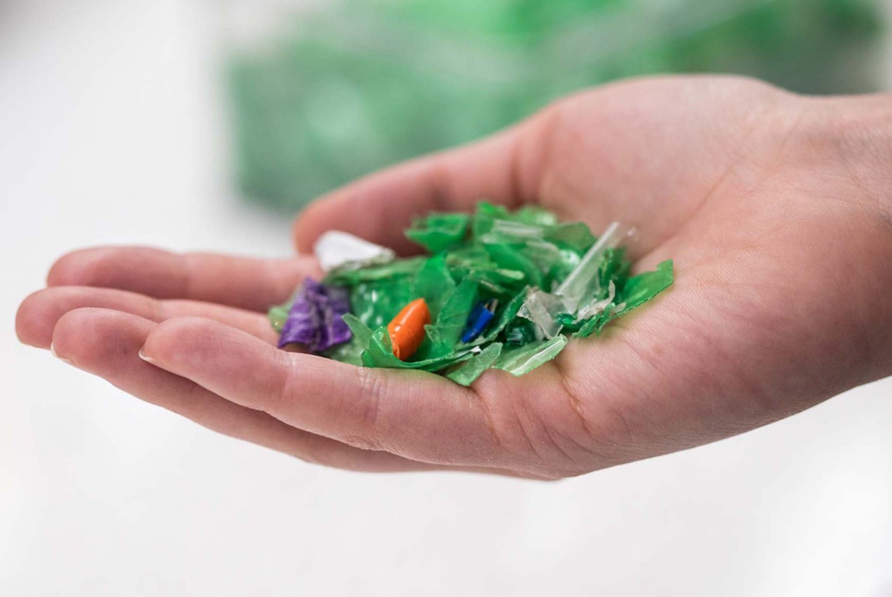 A hand holding an assorted color of shredded plastic waste. 