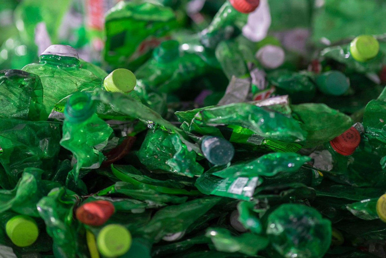 A large pile of flattened green plastic bottles.  