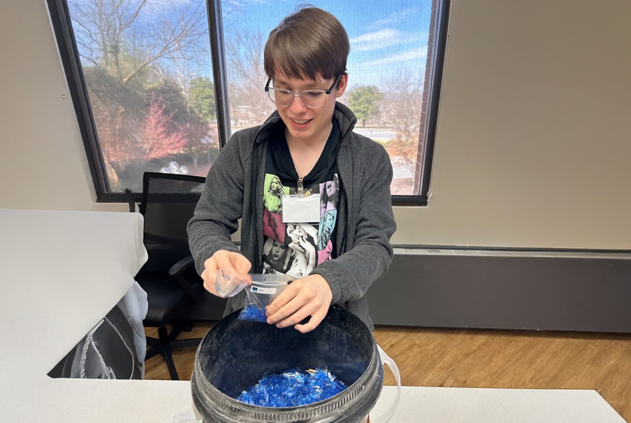 Student fills plastic bags with blue plastic flakes.  
