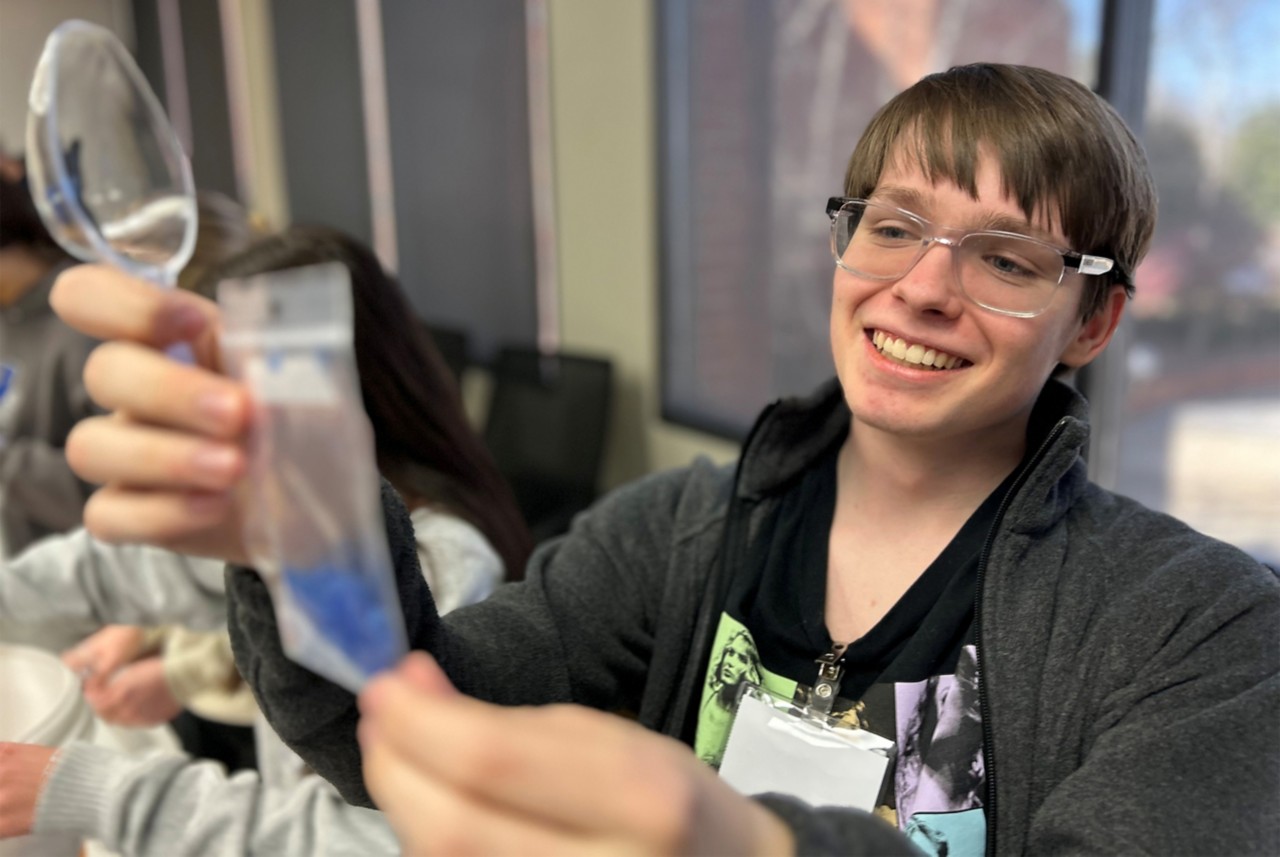  A student fills a sample bag with blue plastic flakes.  