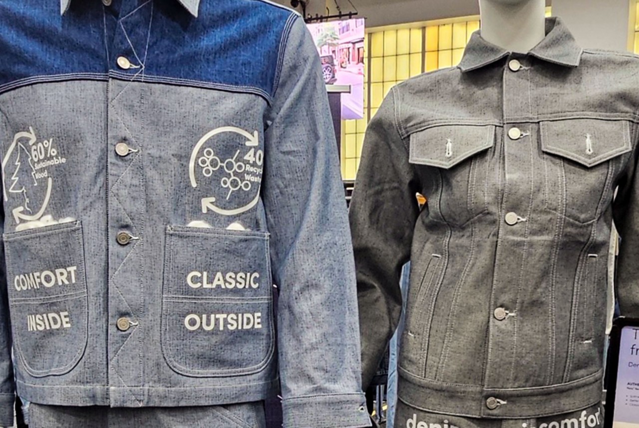  Closeup of two denim jackets, with one of them featuring informative text about the sustainability practices of Naia.