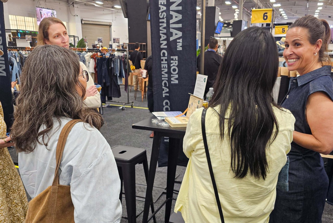 A Naia team member talks to three visitors to the Kingpins booth.