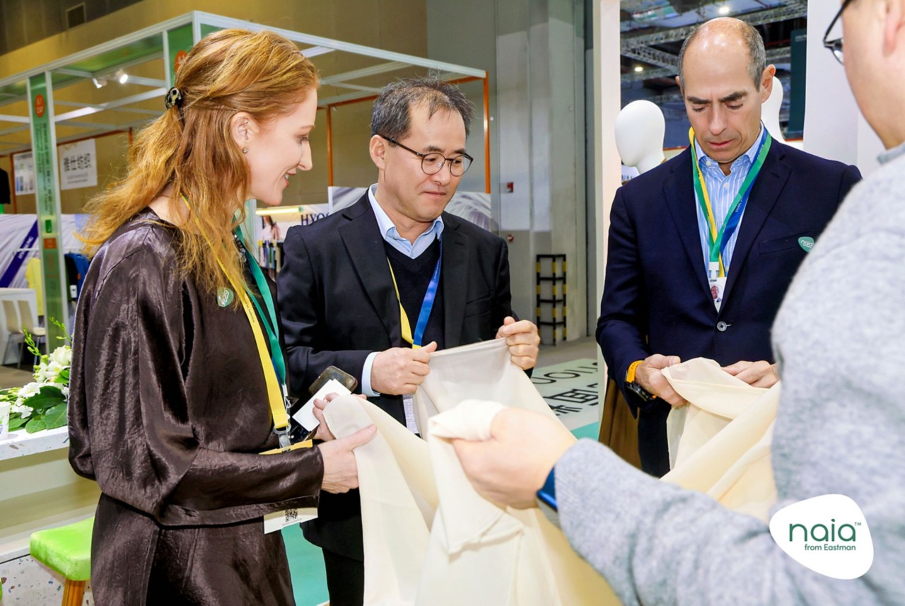 Booth visitors closely inspect Naia Lyte fabric swatches. 