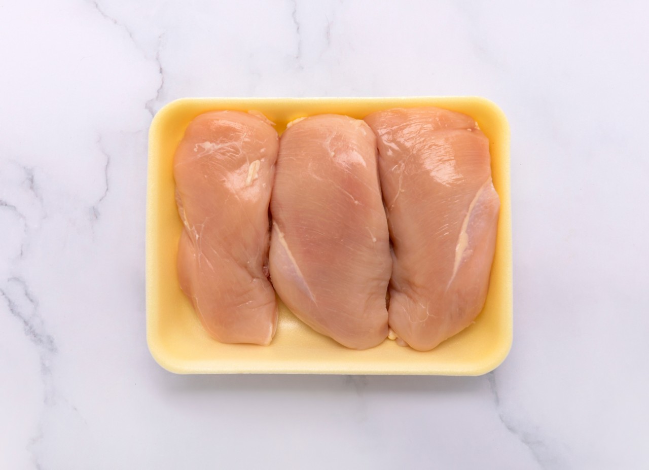 Raw chicken sits in a yellow protein tray. 