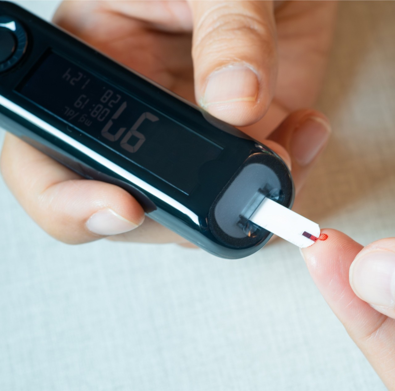 A person using a black blood glucose meter.   