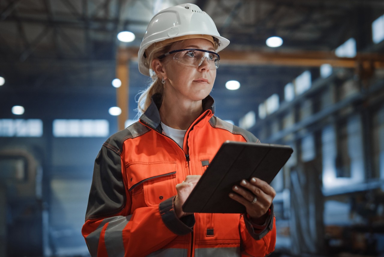 Safety coordinator wearing personal protective equipment and holding a tablet. 