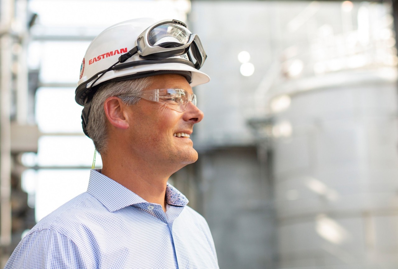 Man wearing a hard hat, lab coat and safety googles. 